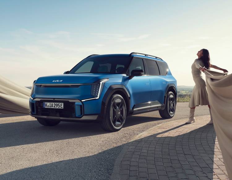 Frau tanzt um einen blauen Kia EV9.