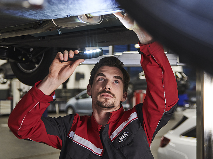 Mechanic repairs something on the engine under the car