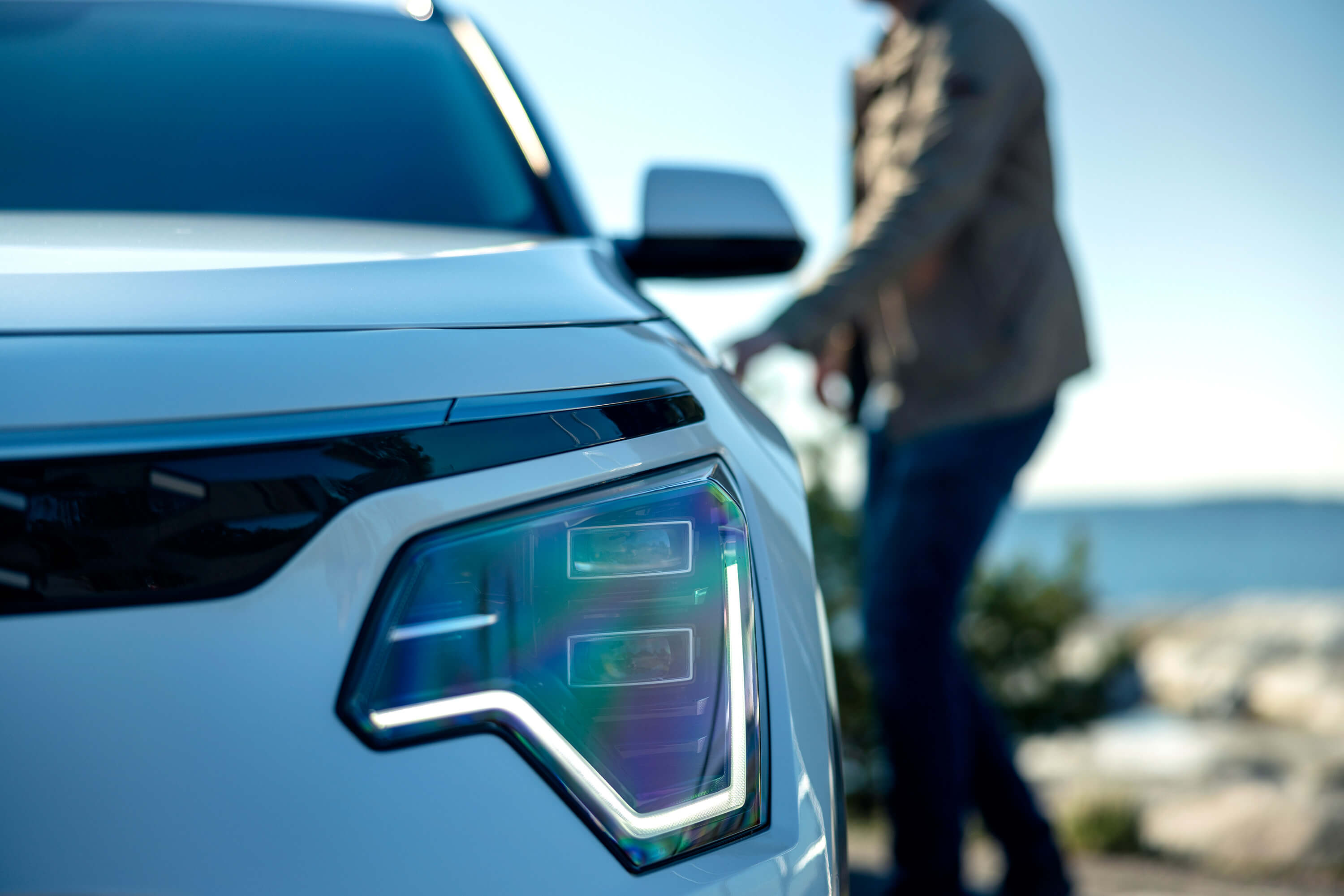 En person på en strand med en sup under armen, i förgrunden Kia Niro EV.