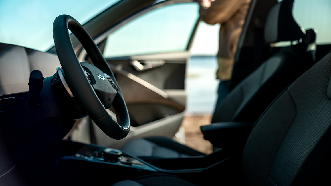 Frontinteriören i Kia Niro EV, i bakgrunden syns en person på en strand.