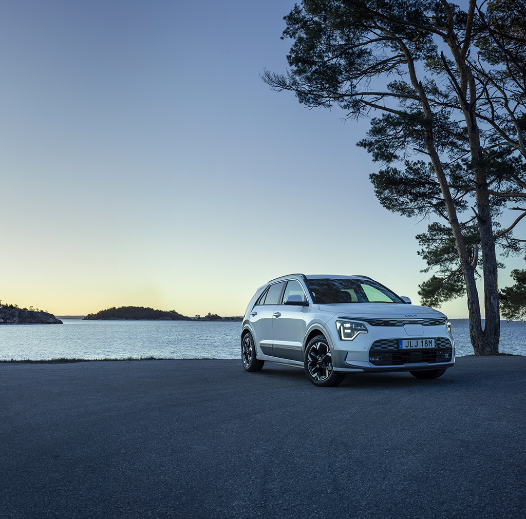 Nya Kia Niro EV står på en parkering vid vattnet i skymningen.