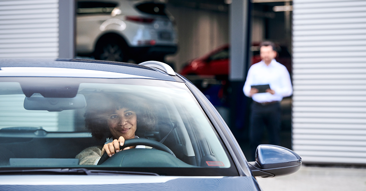 Woman in a Kia EV smiling after having her car serviced