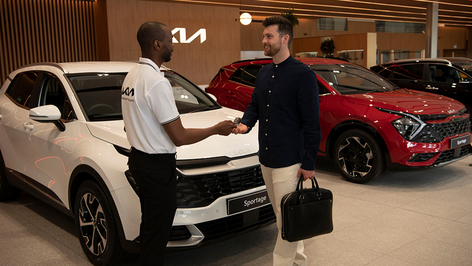 Models shaking hands in a Kia dealership