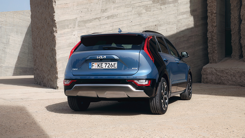 Kia niro EV back view with model walking towards it