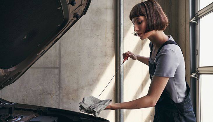 Female vehicle technician checking oil levels